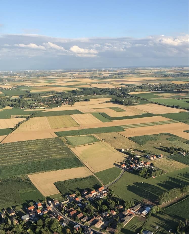 Luchtfoto van het landschap nabij Brussel met velden en een dorp, genomen tijdens een ballonvaart vanuit Tienen door Filva Ballonvaarten